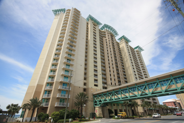 View of large condo building from street, two toned tan building with seafoam trim.