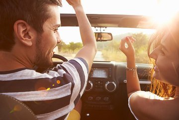 Man and Woman laughing in car, photo taken from backseat.